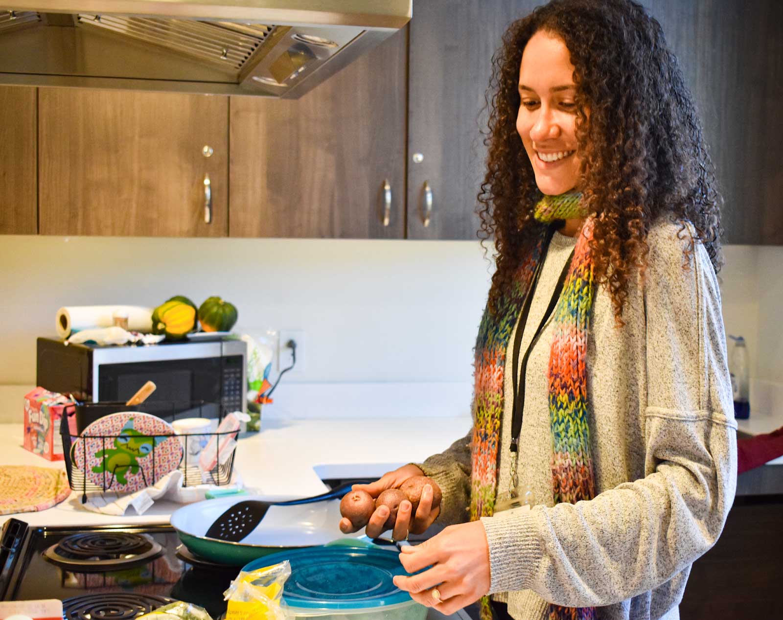 A smiling staff member prepares food in a kitchen.