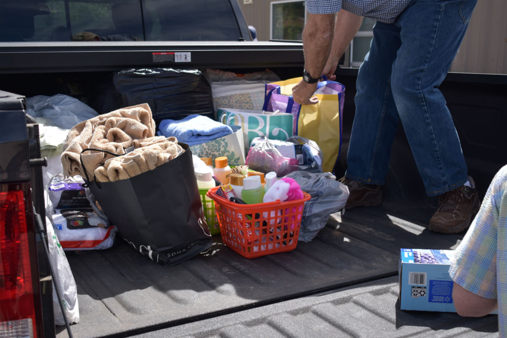 Donations of towels and other home goods in paper bags being loaded off of a pickup truck.