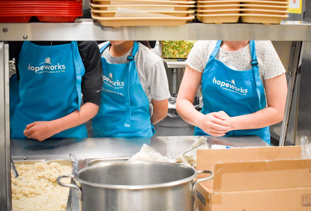 Volunteers in HopeWorks branded aprons serving food in the HopeWorks Day Shelter.